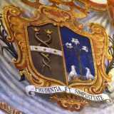 ...composto per met� da due serpenti intrecciati e per l�altra met� da un giglio, un richiamo al cognome Gil, con alla base due colombe e recante l�iscrizione Prudentia et Simplicitate (Saggezza e Semplicit�)